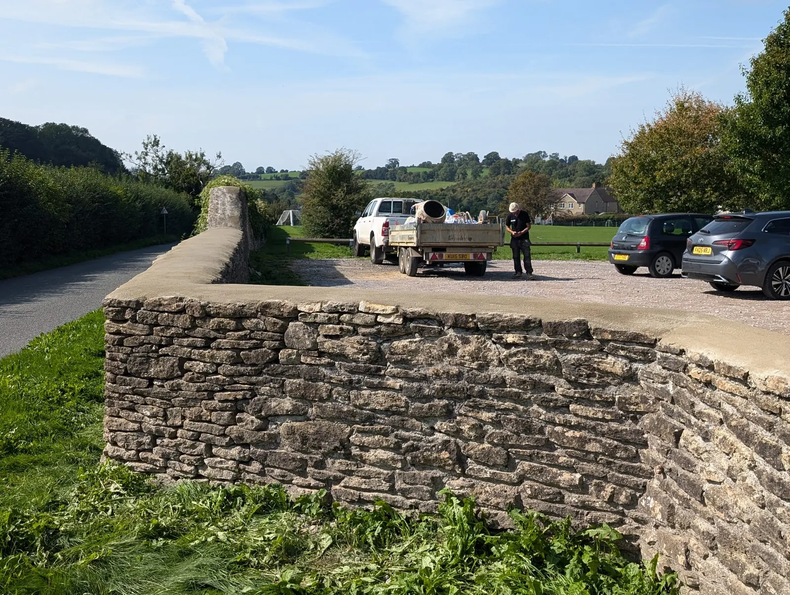 A curved dry stone wall beside a gravel drive