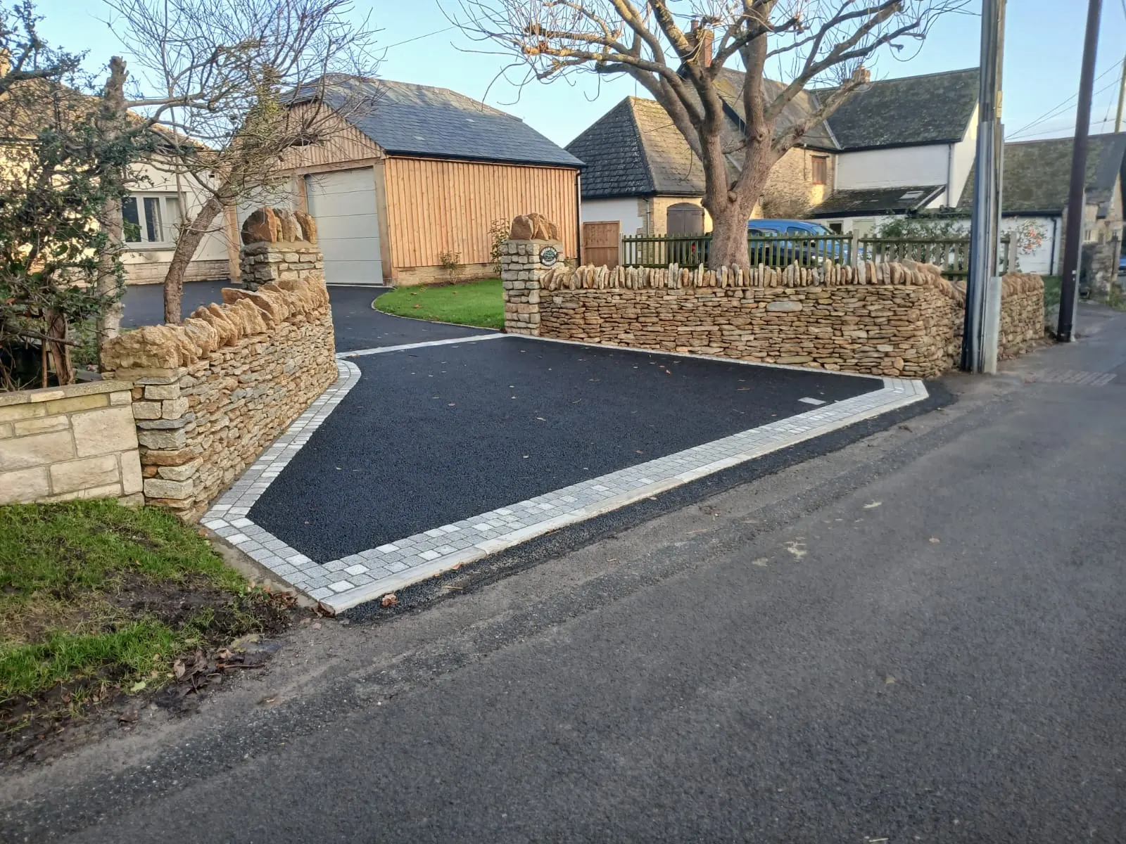 A newly surfaced drive framed by stone walls and gate piers
