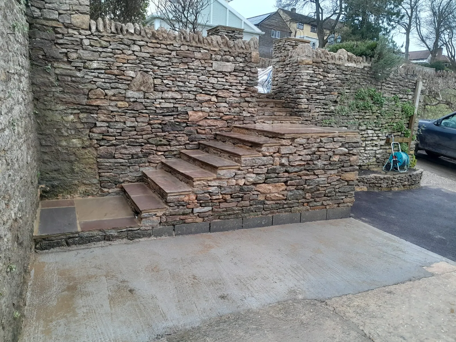 A stone retaining wall with steps built into the corner