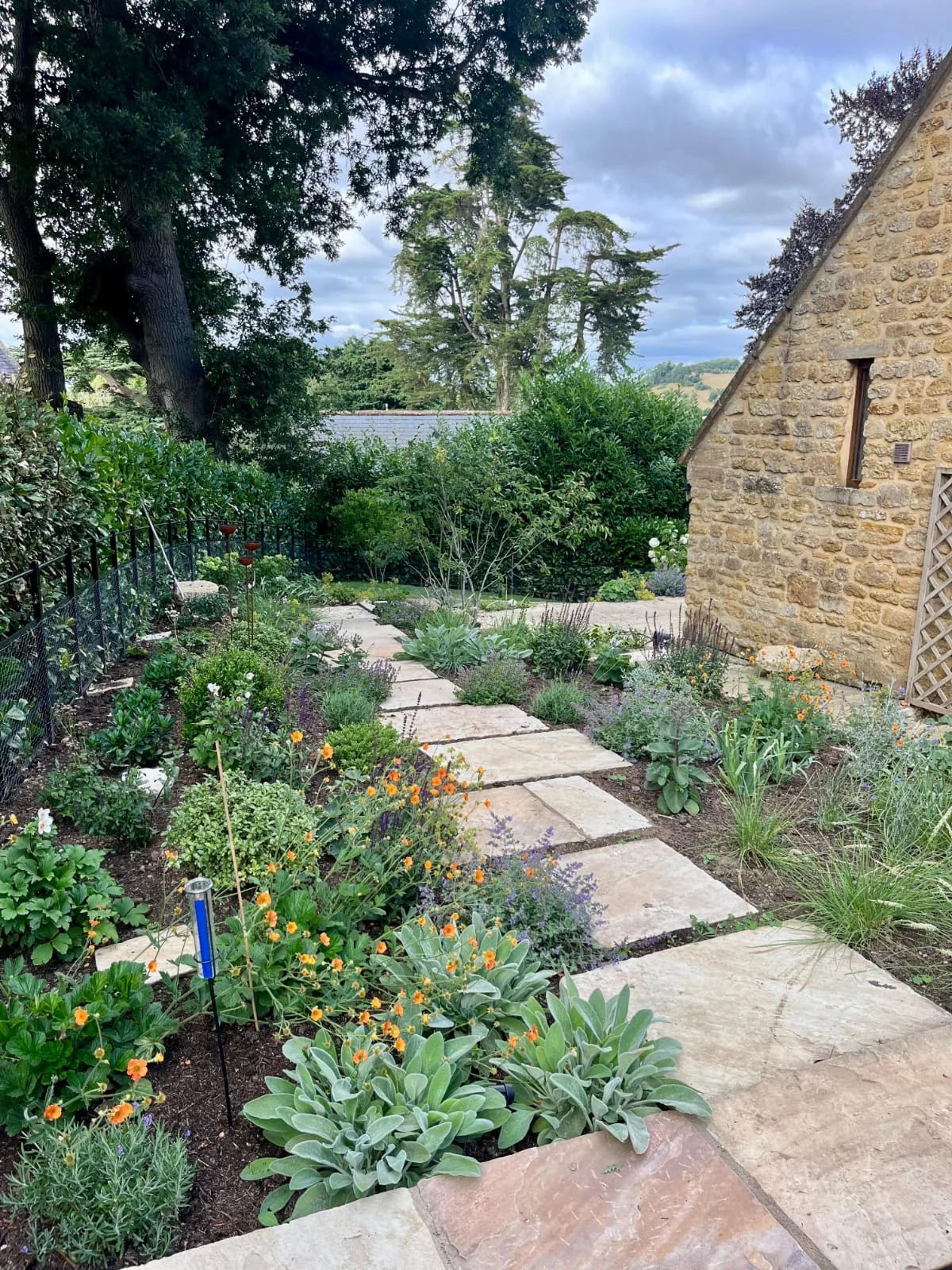 A sandstone path winding through a planted cottage garden