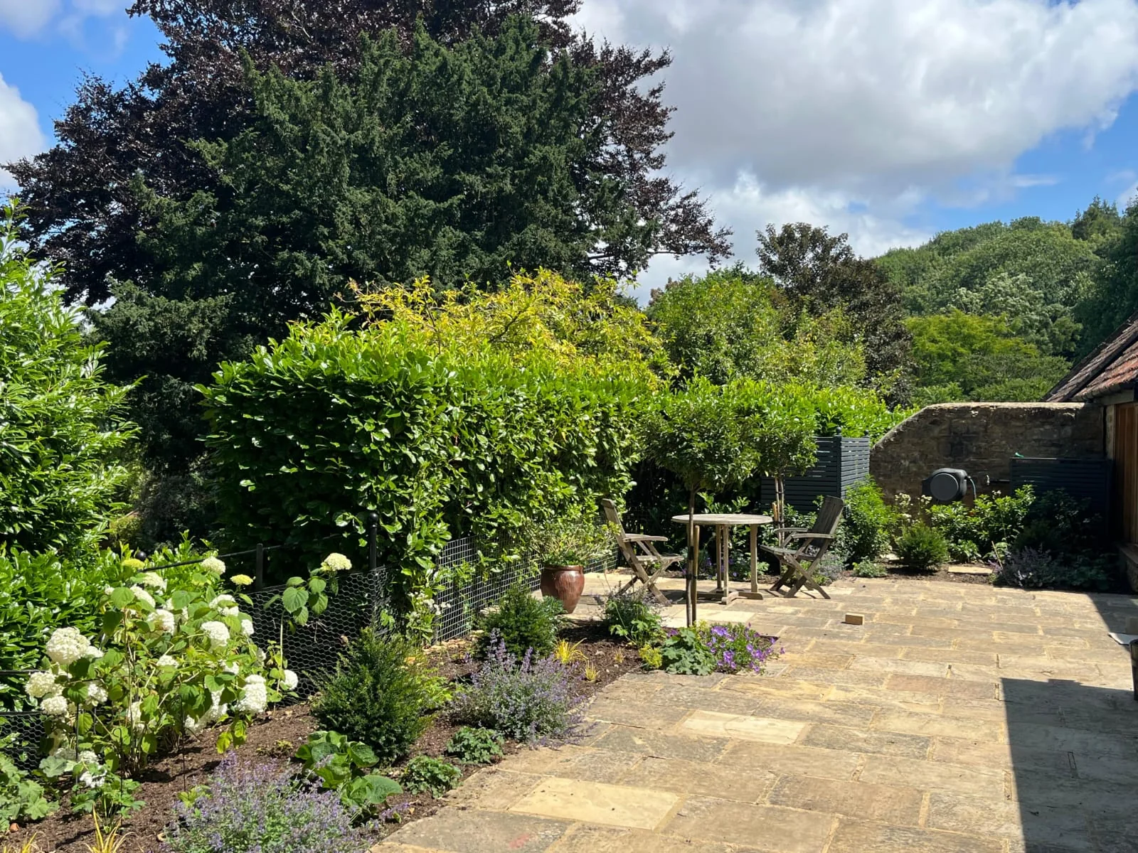 A finished sandstone terrace surrounded by established cottage garden planting