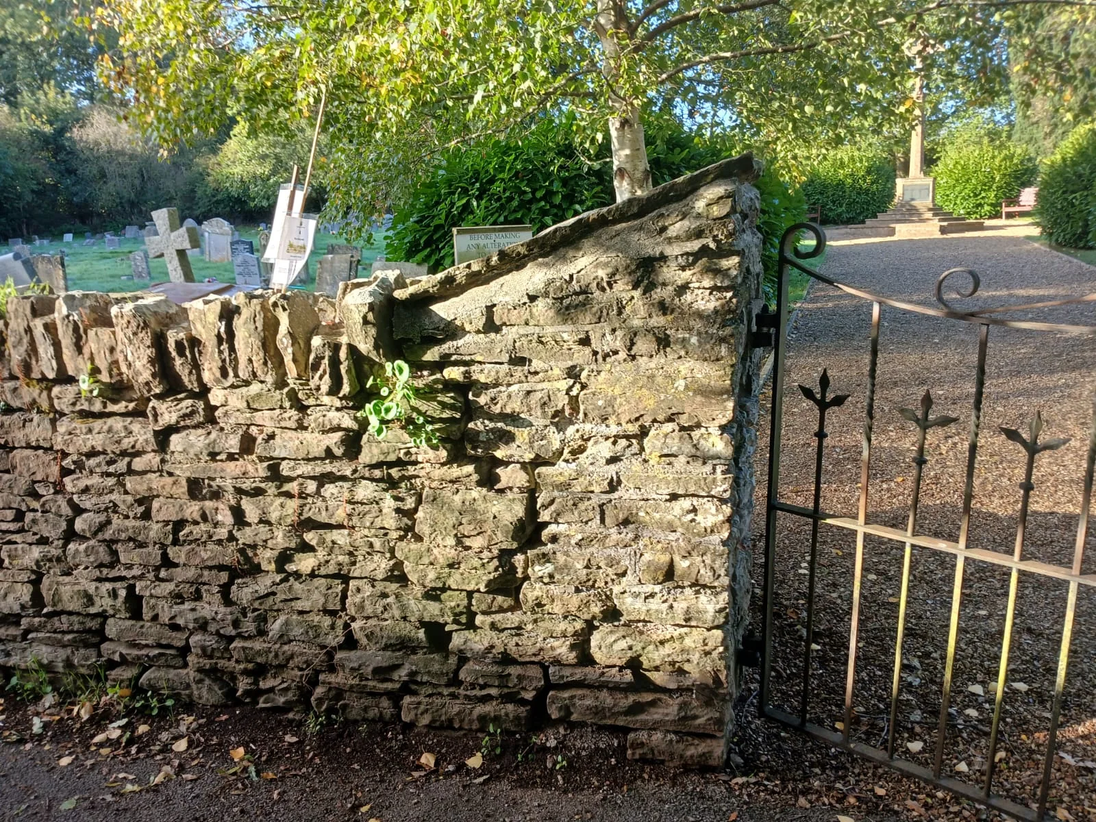 A restored traditional stone garden wall beside an iron gate
